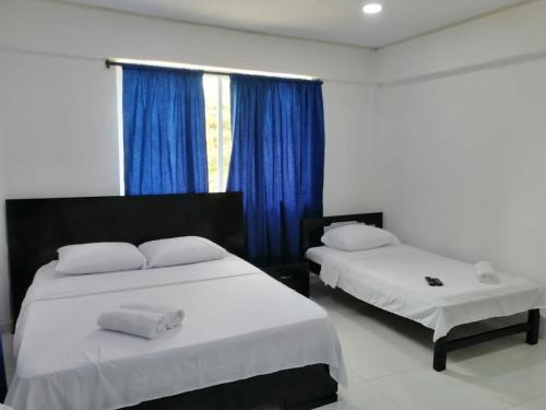 2 Betten in einem Zimmer mit blauen Vorhängen in der Unterkunft FRESH BEACH HOUSE in San Andrés