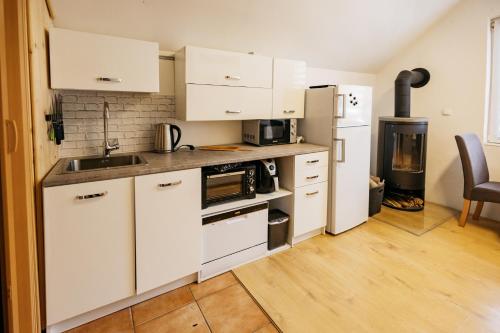uma cozinha com armários brancos, um lavatório e um frigorífico em Mojstranka em Mojstrana