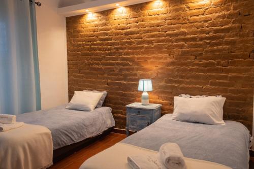 dwa łóżka w pokoju z ceglaną ścianą w obiekcie Casa da Ti´Lola w mieście Évora