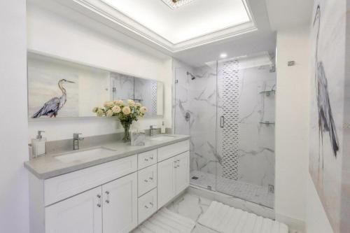 a white bathroom with a shower and a sink at Modern beachfront condo with pool, gym and tennis in Marco Island