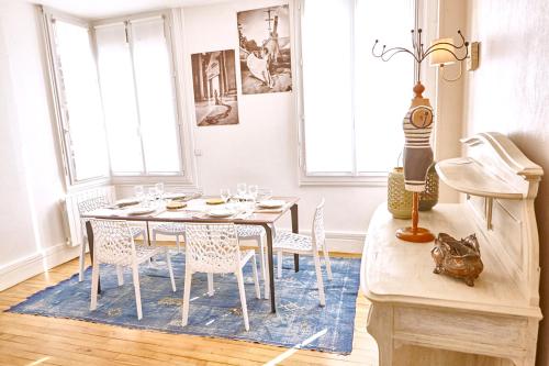 une salle à manger avec une table et des chaises sur un tapis bleu dans l'établissement Etretat hyper centre - Gîte Le Chant des Sirènes - 3 chambres, à Étretat