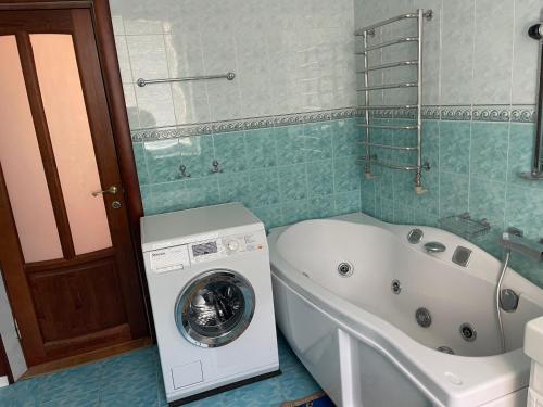 a bathroom with a washing machine and a tub at Lux House in Chernivtsi