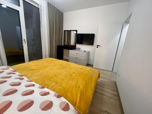 - une chambre avec un lit jaune et une télévision dans l'établissement Ursan Residence, à Uisenteş