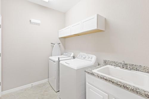 lavadero blanco con lavadora y fregadero en Modern waterfront home in Artesia with pool/gym, en Lely Resort