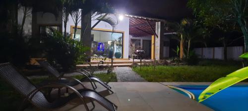 a patio with chairs and a pool at night at Pousada Graboschii, 300mt da praia do Refúgio in Aracaju