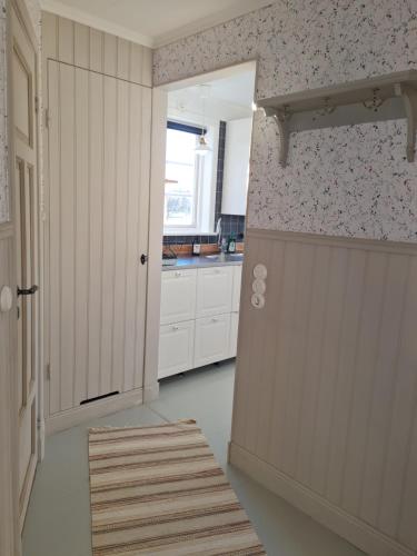 una cocina con armarios blancos y una puerta en una habitación en Grindstugan Högbo en Sandviken