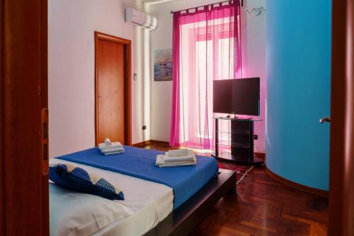 a bedroom with a blue bed and a tv at AmoCatania Apartment in Catania