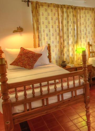 a bed with a wooden frame with a pillow on it at The Fort Bungalow in Cochin