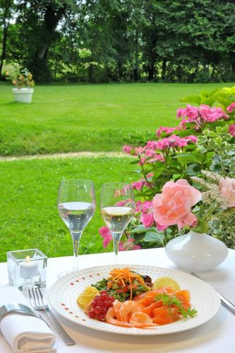 a plate of food on a table with glasses of wine at Château de Bellefontaine - Teritoria in Bayeux