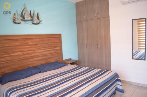 a bedroom with a bed with a wooden head board at Depa en la marina a 5min de la playa by G P S rentas in Mazatlán