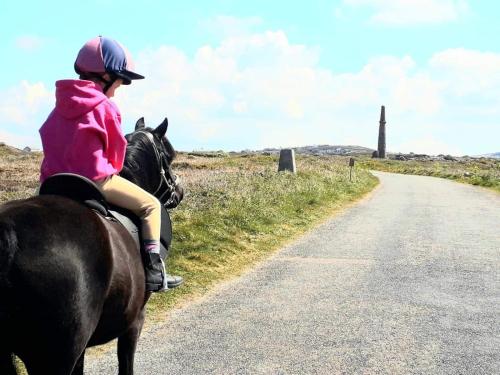 a young child riding a horse down a road at Dollys Den bell tent in St. Just