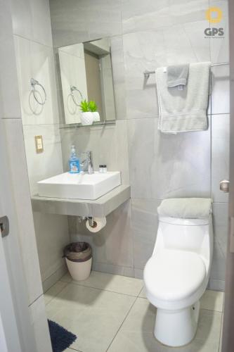 a bathroom with a white toilet and a sink at Depa en la marina a 5min de la playa by G P S rentas in Mazatlán