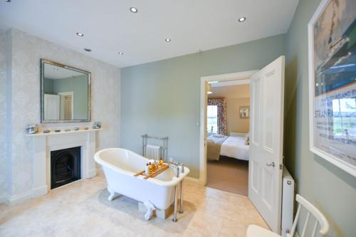 a bathroom with a white tub and a fireplace at High Clachan Farmhouse in Stranraer