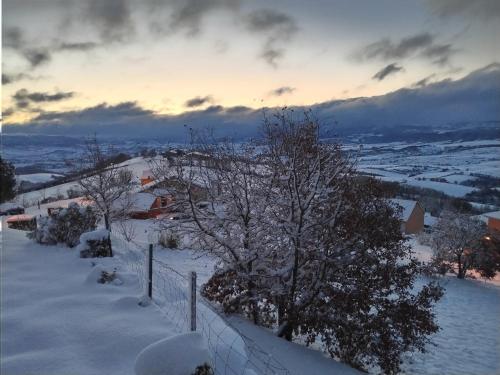 a snow covered hill with a fence and trees at Naudebals in Rebourguil