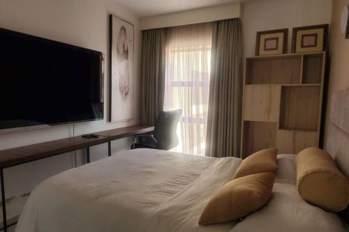 a bedroom with a bed with pillows and a flat screen tv at Astoria 2BR Penthouse [Views of Bliss] in Nairobi