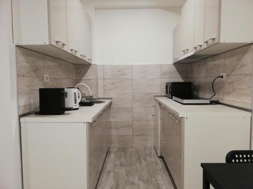 una cocina con armarios blancos y una pared de azulejos en Quince, en Bor