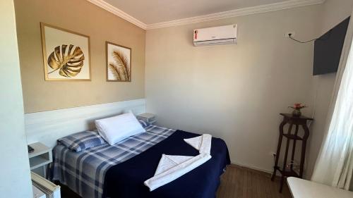 um pequeno quarto com uma cama com um cobertor azul em Suites Carioca em Porto de Galinhas