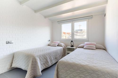 two beds in a white room with a window at Apartamento Sanxenxo Centro in Sanxenxo