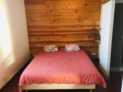 - une chambre avec un lit et un mur en bois dans l'établissement Gîte de la Bastide, à Autignac
