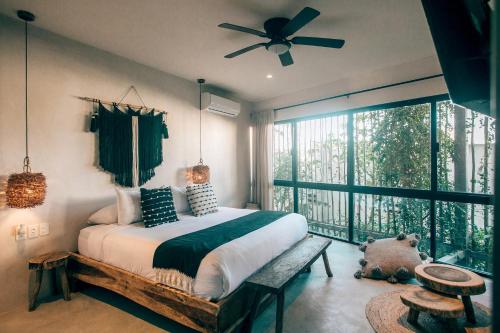 a bedroom with a bed with a ceiling fan and a window at Vida Jungle Apart 7 with special fee to access Hotel Bardo in Tulum