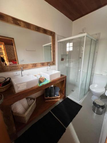 a bathroom with two sinks and a shower and a mirror at Pousada Vale do Café in Bueno Brandão