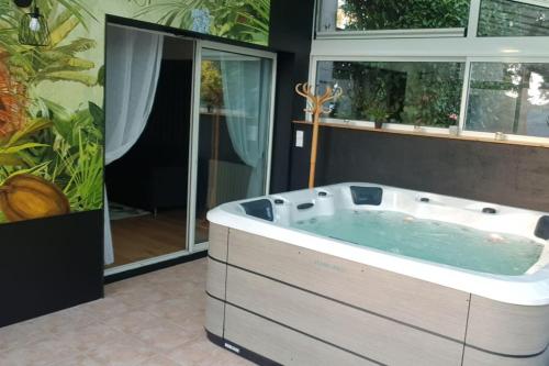 a hot tub in a bathroom with a window at Maison paisible Rennes sud avec jaccuzzi sur réservation in Noyal-Châtillon-sur-Seich