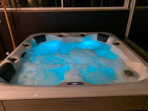 a bath tub filled with blue water at Maison paisible Rennes sud avec jaccuzzi sur réservation in Noyal-Châtillon-sur-Seich