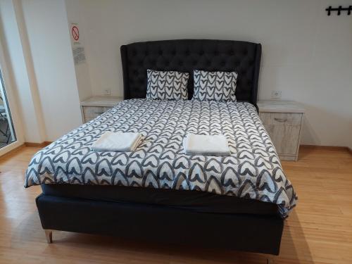 una camera con un grande letto con testiera nera di City Passage Apartments- Rooms a Novi Sad