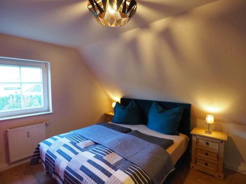 ein Schlafzimmer mit einem Bett mit blauen Kissen und einem Fenster in der Unterkunft Fewo Karasek in Oybin mit Panormablick, Kammlage in Hain