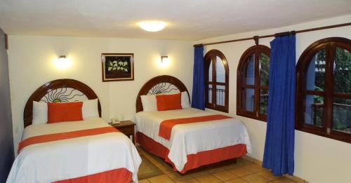 2 camas en una habitación con 2 ventanas en Hotel Jardines Del Carmen, en San Cristóbal de Las Casas