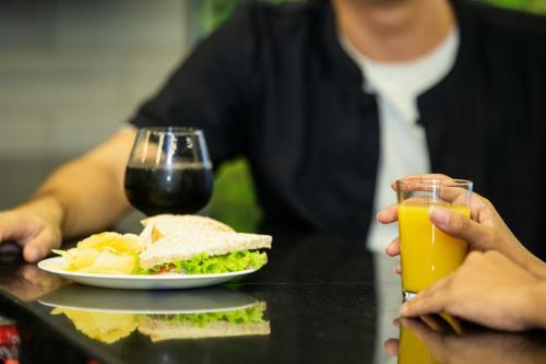 a person holding a plate of sandwich and a glass of orange juice at ibis Styles Belem Nazare in Belém