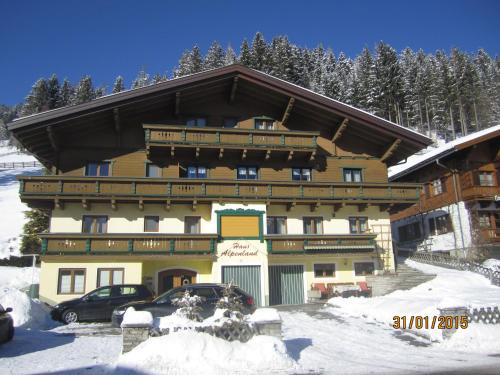 a large building in the snow with cars parked in front at Haus Alpenland in Wagrain