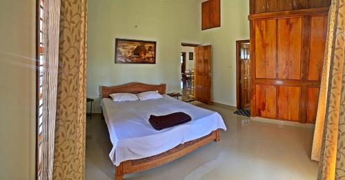 1 dormitorio con 1 cama con sábanas blancas y muebles de madera en Monappa Estate - Beautiful Riverside Farm house in Udupi, en Udupi