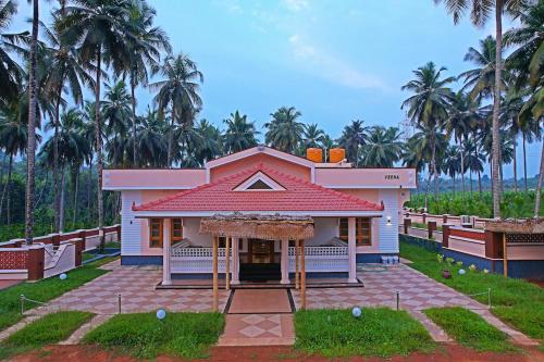 a small house with a red roof and palm trees at Monappa Estate - Top Rated - Luxury Villa in Udupi