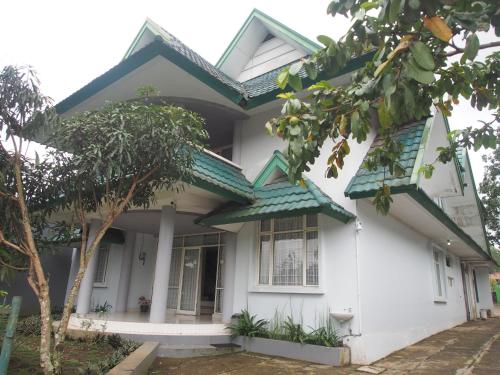 une maison blanche avec un toit vert dans l'établissement Rumah Ijau - Halal Homestay, à Padangluar
