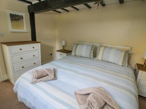a bedroom with a white bed with towels on it at Mill End in Nantwich