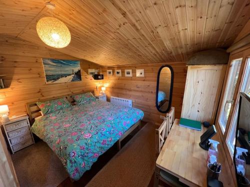 a bedroom with a bed in a wooden cabin at Cosy Cabin, hidden from the main house - Sleeps 2 - EV in Hawkinge