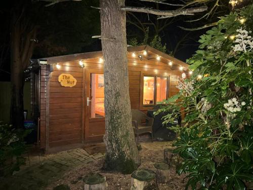 a small wooden cabin with a tree in front of it at Cosy Cabin, hidden from the main house - Sleeps 2 - EV in Hawkinge