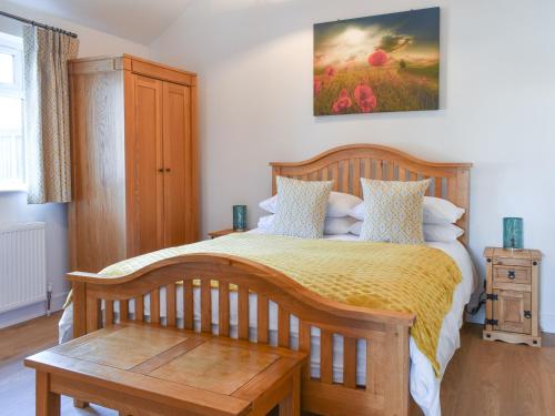 a bedroom with a wooden bed with a yellow bedspread at South Downs Lodge in Droxford