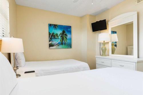 a white bedroom with two beds and a mirror at Lei Lani Village 114 in Orange Beach
