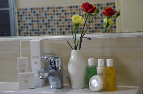 a bathroom sink with a vase with flowers in it at Norfolk Towers Serviced Apartment -Nairobi, City Centre CBD in Nairobi