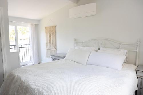 a white bedroom with a white bed and a window at 3Bdrm Quiet Private Victorian Style Brand New Gorgeous townhouse in Burlington in Burlington