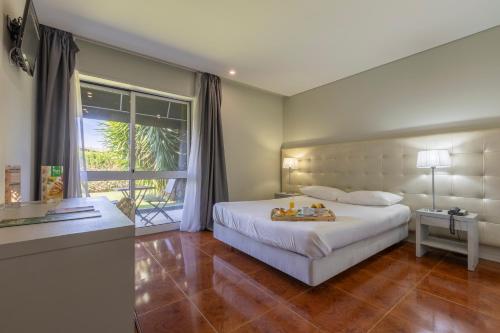 een slaapkamer met een groot wit bed en een raam bij Hotel Vila in Guimarães