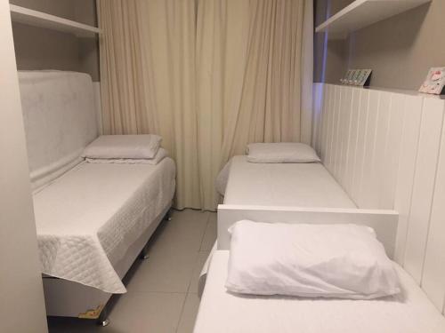 two beds in a small room with white sheets at Apartamento no Complexo Iberostate in Acu da Torre