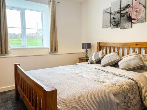 a bedroom with a large bed and a window at Four Burrows Bungalow in Chacewater