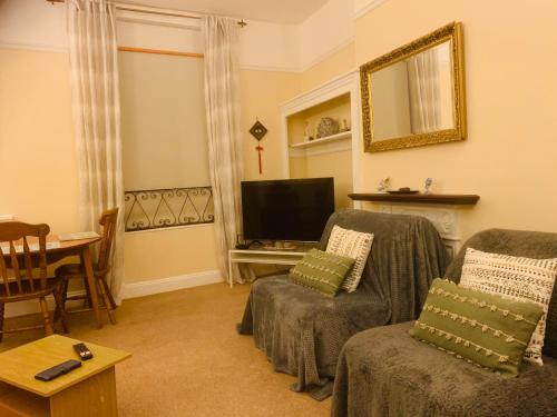 a living room with two chairs and a flat screen tv at 22A Cosy double bed town centre in Wellingborough