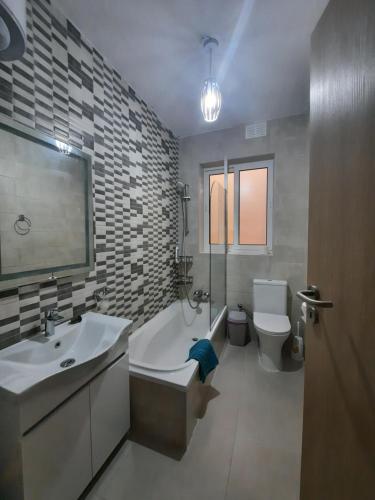 La salle de bains est pourvue d'une baignoire, d'un lavabo et de toilettes. dans l'établissement One Bedroom apartment, à San Ġiljan