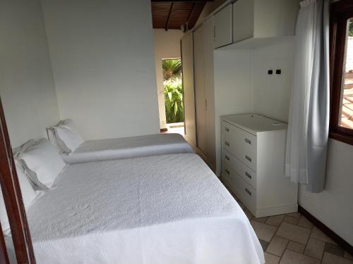 una piccola camera con un letto bianco e una finestra di CASA MARAVILHOSA à BEIRA MAR EM ANGRA DOS REIS ad Angra dos Reis