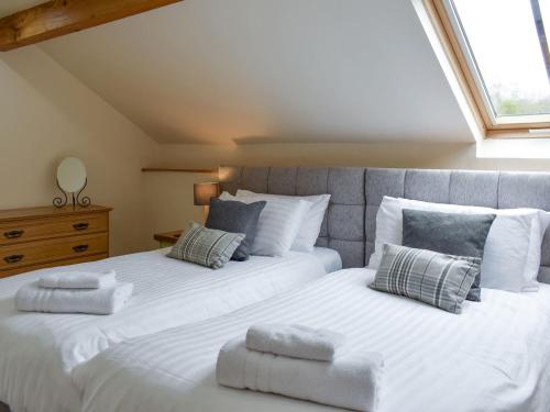 two beds in a bedroom with white sheets and pillows at Stallion Barn in Crosby Garrett