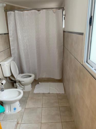 a bathroom with a toilet and a shower curtain at Parque jardín in La Falda